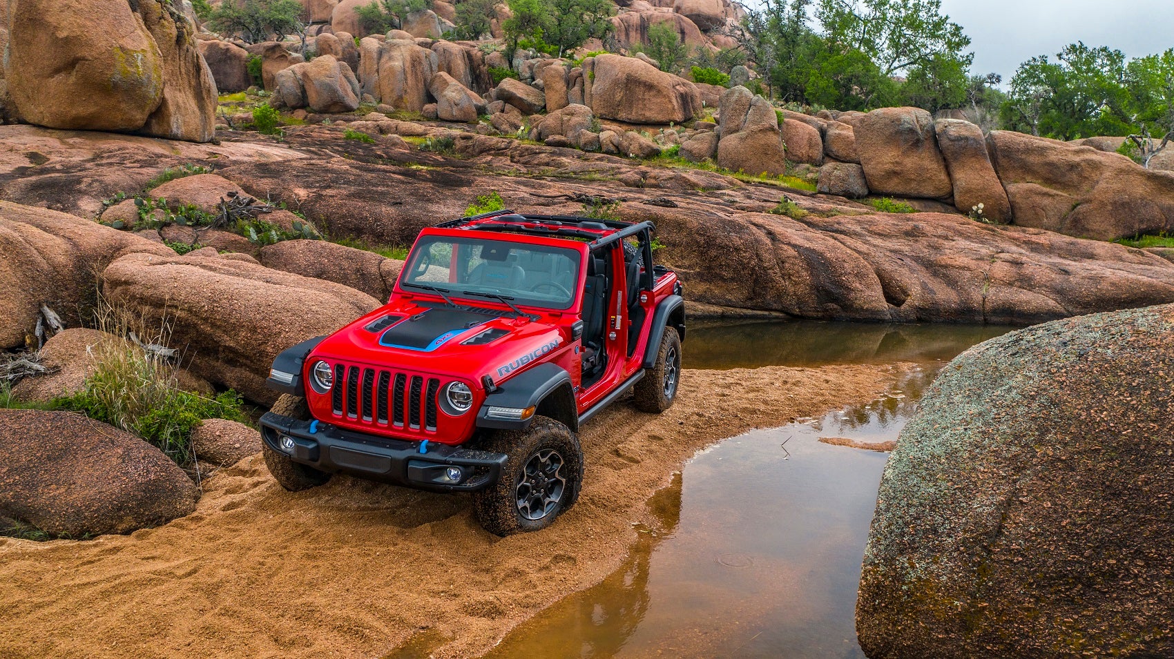Red Jeep Wrangler climbing up a dirt trail