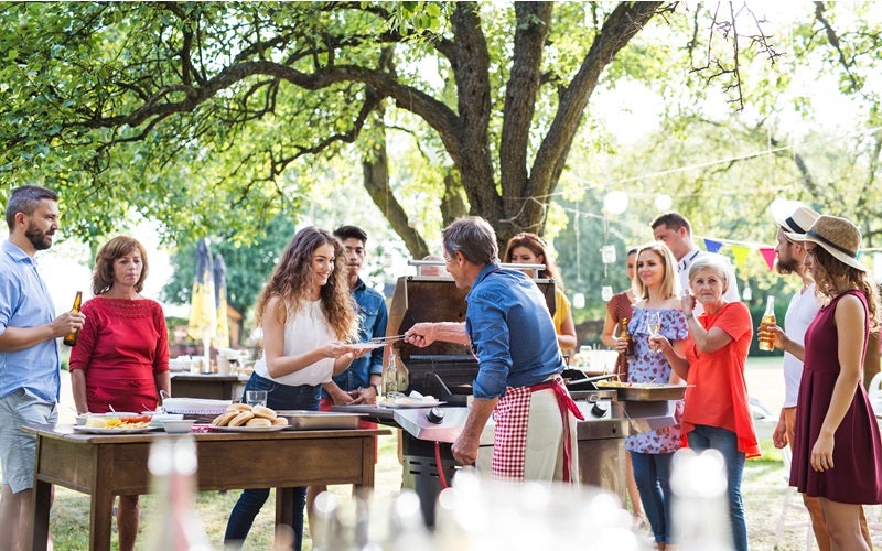 Family picnic in a park with person on the grill handing out food