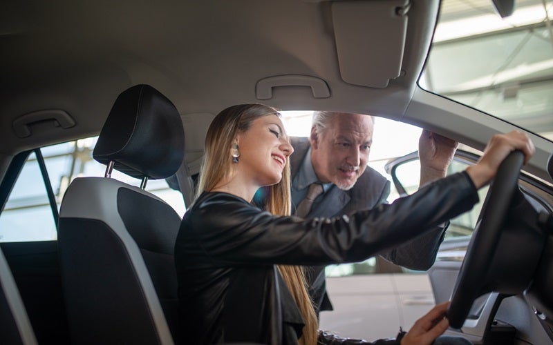 Sales consultant talking to customer inside a car