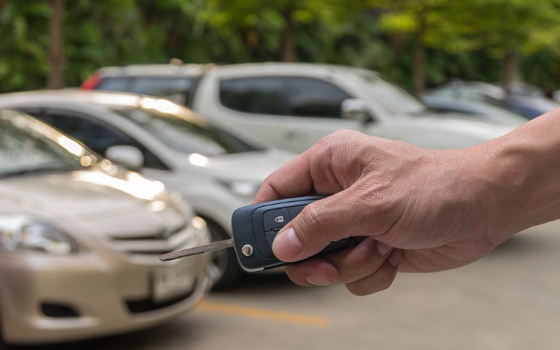 Key fob being held in front of a used car lineup